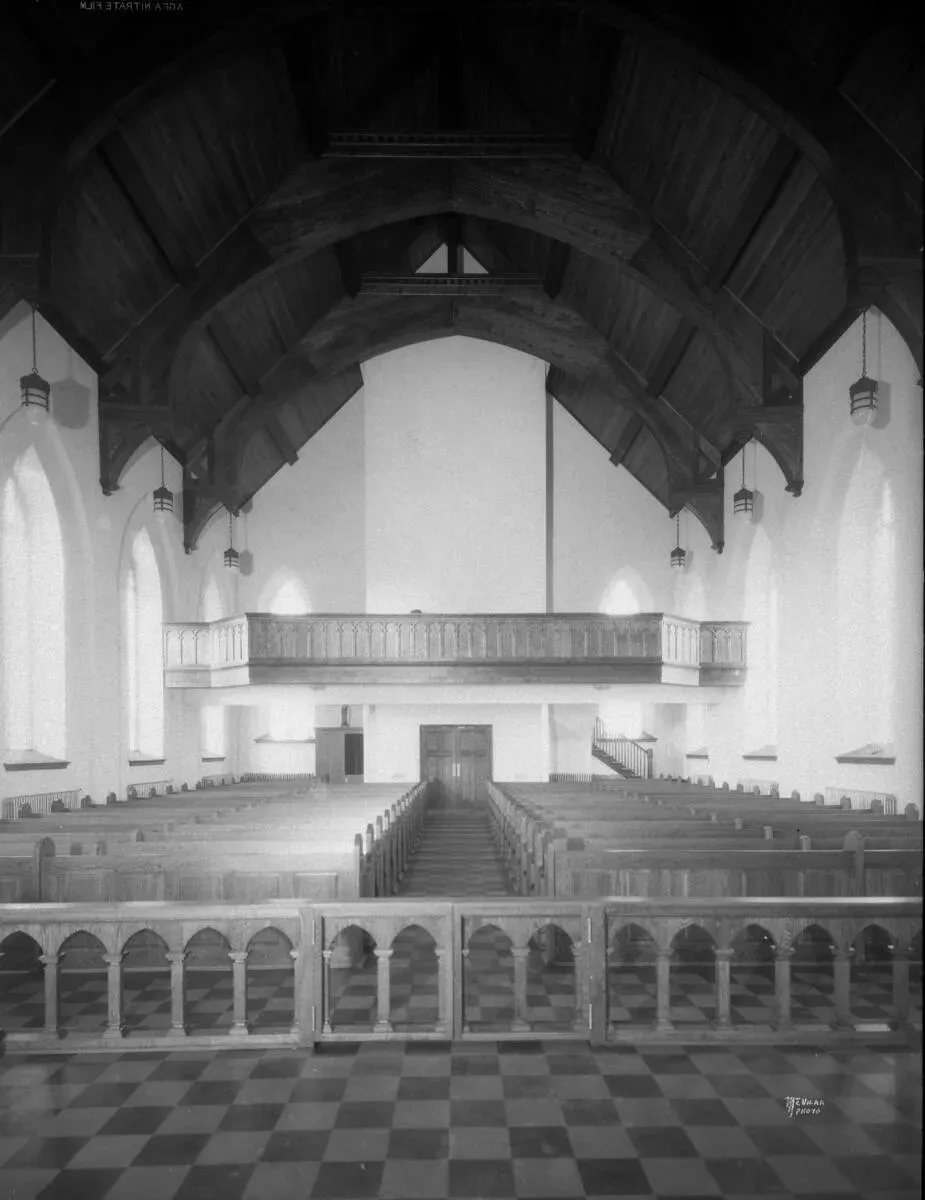 The rebuilt church seen from the altar: pews, a choir loft and a dark hammerbeam roof