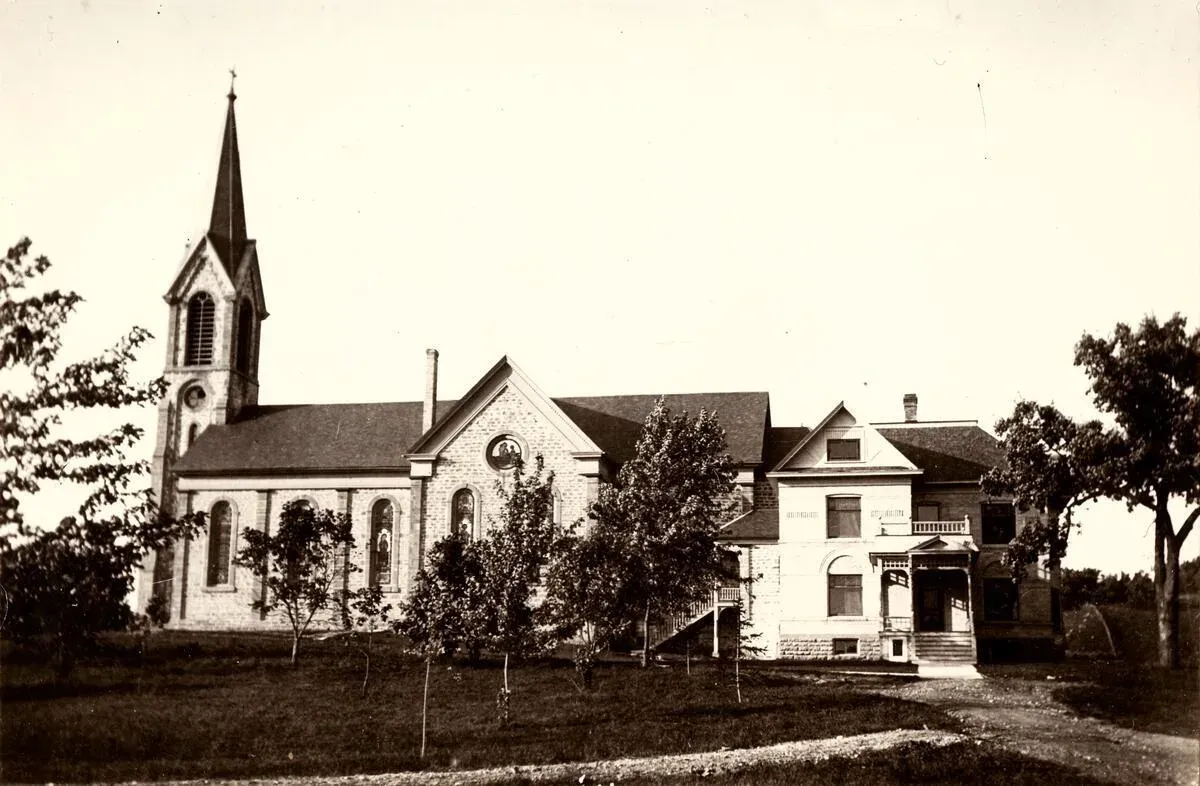 St. Norbert’s stone church with its spire, and the rectory beside it, in 1915